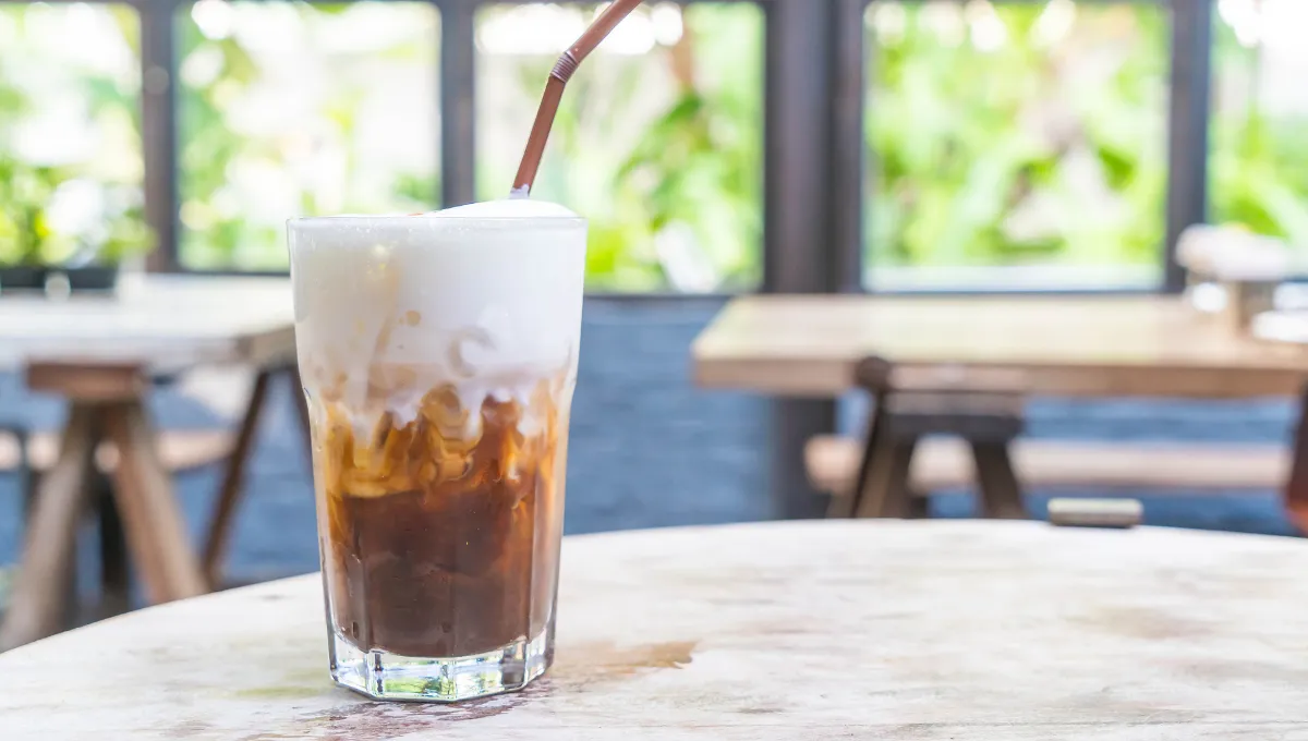 A kép bal oldalán egy jeges latte van egy asztalon